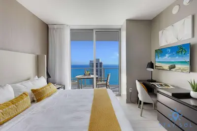 a bedroom with a bed and a desk with a view of the ocean at High Floor 2BR -2 BA - Resort Fees & Parking Incl in Hollywood