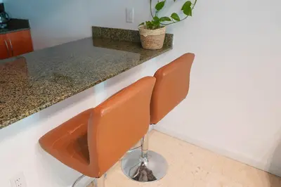 a kitchen with two brown chairs at a counter at 4 bed full condo in Miami with skyline & sea view in Miami