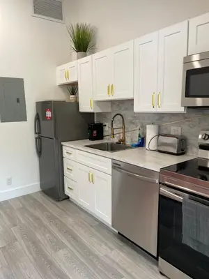 a kitchen with white cabinets and a black refrigerator at Modern Riverview Apartments in Fort Lauderdale