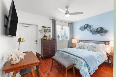 a bedroom with a bed and a table and a tv at The Pearl Beachside Apartments on Hollywood Beach in Hollywood