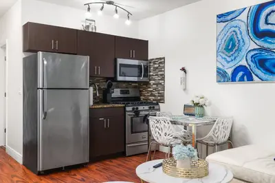 a kitchen with a stainless steel refrigerator and a table at The Pearl Beachside Apartments on Hollywood Beach in Hollywood