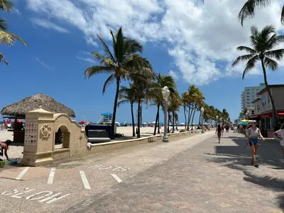 a beach with palm trees and people walking down a sidewalk at The Pearl Beachside Apartments on Hollywood Beach in Hollywood