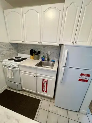 a kitchen with white cabinets and a sink and a refrigerator at Downtown FTL apartments on the River in Fort Lauderdale