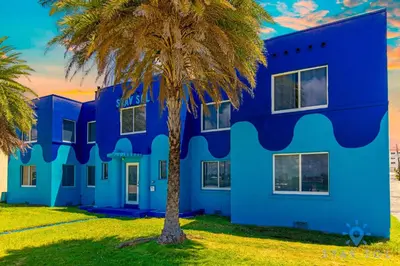 a blue building with a palm tree in front at Free Parking - Bay View - Pool - Step To Beach in Hollywood