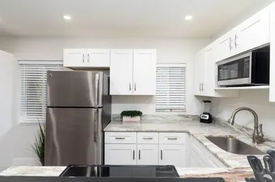a kitchen with white cabinets and a stainless steel refrigerator at The Hideaway at Lake Ridge 3 in Fort Lauderdale