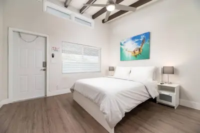 a white bedroom with a bed and a painting on the wall at The Hideaway at Lake Ridge 2 in Fort Lauderdale