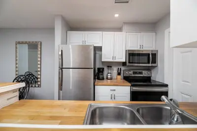 a kitchen with white cabinets and a stainless steel refrigerator at The Palms at Middle River Terrace 3 in Fort Lauderdale