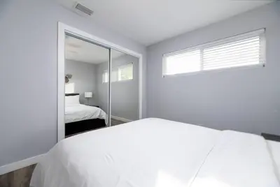a white bedroom with a bed and a mirror at The Palms at Middle River Terrace 4 in Fort Lauderdale