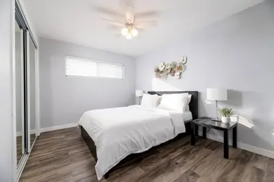 a white bedroom with a bed and a ceiling fan at The Palms at Middle River Terrace 4 in Fort Lauderdale