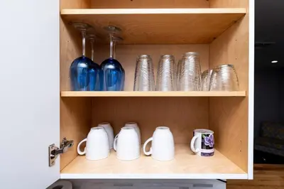 a cupboard with blue and silver dishes and mugs at The Palms at Middle River Terrace 4 in Fort Lauderdale