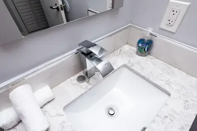 a white bathroom with a sink and a mirror at The Palms at Middle River Terrace 4 in Fort Lauderdale