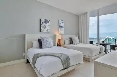 a white bedroom with two beds and a balcony at Penthouse Condo at Lyfe Resort and Residences in Hollywood