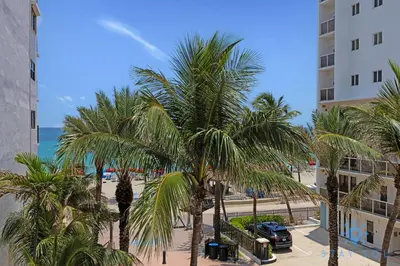 a view of a beach with palm trees and a building at Ocean View - Balcony - Rooftop Pool - Hollywood Beach in Hollywood