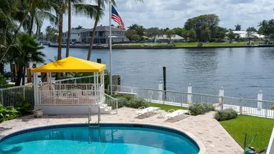 a swimming pool with an umbrella next to a river at WaterFront 4BR 3B,Intercoastal,Pool,5 min walk to beach-7 in Fort Lauderdale