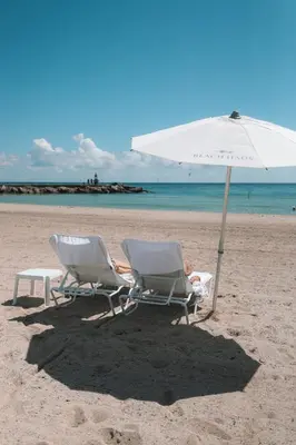 two chairs and an umbrella on a beach at Beach Haus Residences in Bal Harbour
