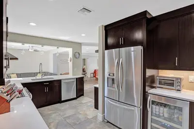 a kitchen with a stainless steel refrigerator and wooden cabinets at Hollywood Villa close to the BEACH w/HEATED POOL in Hollywood