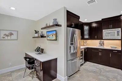 a kitchen with wooden cabinets and a stainless steel refrigerator at Hollywood Villa close to the BEACH w/HEATED POOL in Hollywood