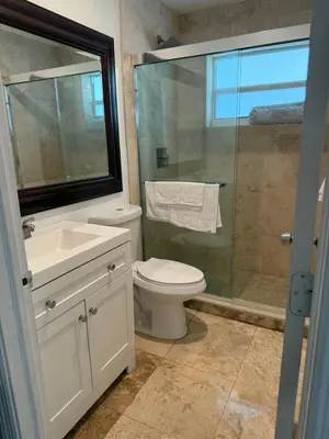 a bathroom with a toilet and a glass shower at El Shaddai Faithfully Beach in Hollywood