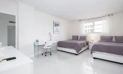 a white bedroom with two beds and a desk at Beautiful 2 Bedroom Apartment on Hollywood Beach in Hollywood