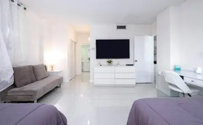 a white bedroom with a couch and a tv in it at Beautiful 2 Bedroom Apartment on Hollywood Beach in Hollywood