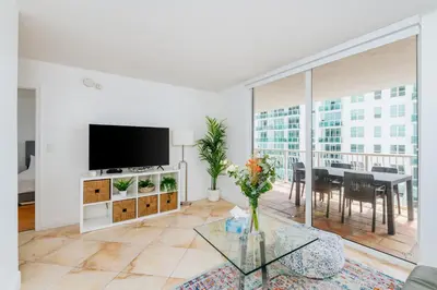 a living room with a flat screen tv and a table at Amazing 2 BR APT at Brickell, Free Parking in Miami