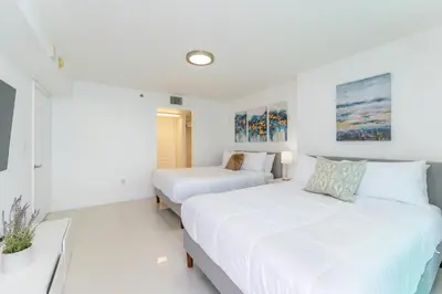 two beds in a room with white walls at Bright and Cozy 2BR at Brickell, Free Parking in Miami