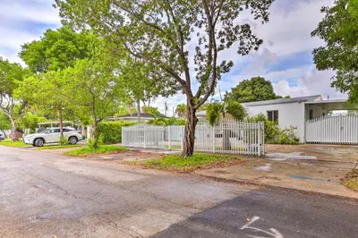 a house with a white fence and a tree at Central Miami Home about 10 Mi to Local Beaches! in Miami