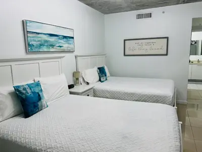 two beds in a room with white walls at Classy 2BD 2BTH at Midblock with FREE PARKING in Miami