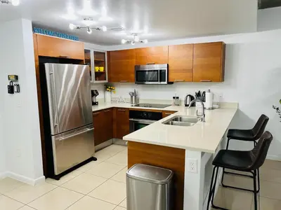 a kitchen with a stainless steel refrigerator and wooden cabinets at Classy 2BD 2BTH at Midblock with FREE PARKING in Miami