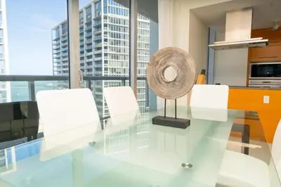 a glass table with white chairs and a fan at W Hotel Miami Stunning Private Condo With Access to All Hotel Amenities in Miami
