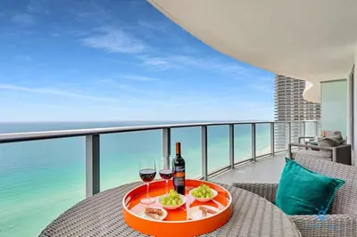 a table with wine glasses and a plate of food on a balcony at Insane Ocean View Balcony- Beachfront Resort - Pools in Hollywood