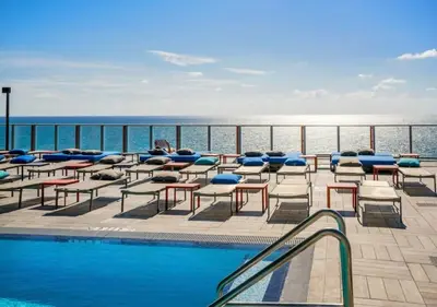 a pool with chairs and tables and the ocean at Insane Ocean View Balcony- Beachfront Resort - Pools in Hollywood