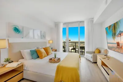 a bedroom with a bed and a couch and a table at Infinite Views with Amazing Pool plus Gym, Near Beach in Hallandale Beach