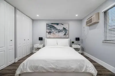 a white bedroom with a large bed and two tables at Shell on the Beach 104 - RENOVATED in Hollywood