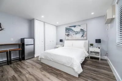 a white bedroom with a bed and a refrigerator at Shell on the Beach 104 - RENOVATED in Hollywood