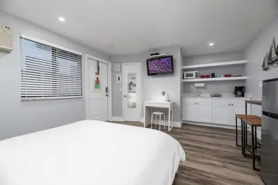 a bedroom with a white bed and a kitchen at Shell on the Beach 104 - RENOVATED in Hollywood