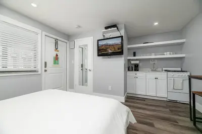 a white bedroom with a bed and a kitchen at Shell on the Beach 106 - RENOVATED in Hollywood