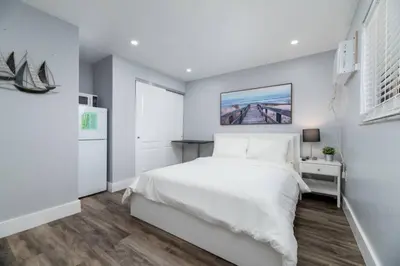 a white bedroom with a bed and a kitchen at Shell on the Beach 102 - RENOVATED in Hollywood