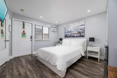 a white bedroom with a large white bed and wooden floors at Shell on the Beach 103 - RENOVATED in Hollywood