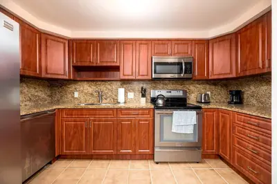 a kitchen with wooden cabinets and stainless steel appliances at Shell on the Beach 101 in Hollywood