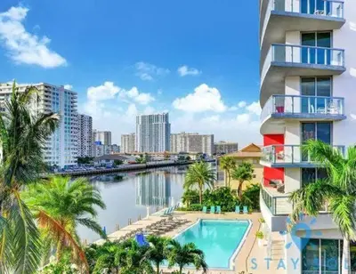 a building with a swimming pool next to a body of water at Infinite View, Balcony, Gym, Amazing Pool in Hallandale Beach