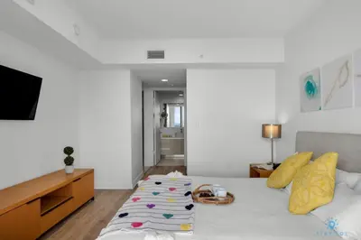 a bedroom with a white bed with a couch at Infinite View with Balcony,Pool plus Near Beach in Hallandale Beach