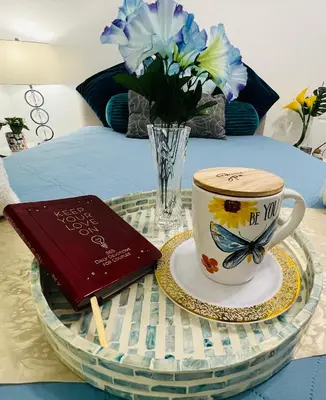 a table with a coffee cup and a book and flowers at Relax 521- at the side in Miami