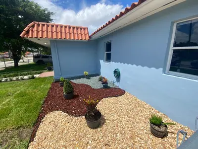 a backyard with potted plants and a blue house at Relax 521 in Miami