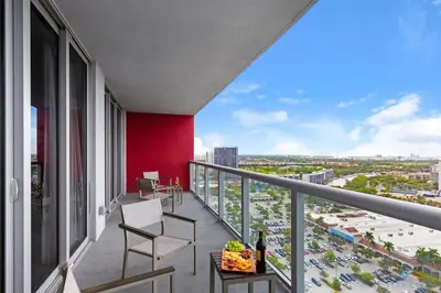 a balcony with chairs and a red wall at Infinite View and Balcony with Pool, Near Beach in Hallandale Beach