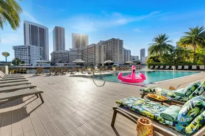 a swimming pool with chaise lounges and a pink poolvisorvisorvisor at Upper studio with Balcony,Pool and Gym, Near Beach in Hallandale Beach