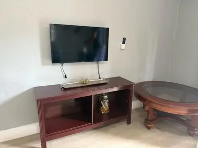 a tv sitting on top of a wooden stand with a table at Modern cozy home with private patio - Sleeps 6 in Miami
