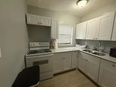 a kitchen with white cabinets and a stove and a sink at Modern cozy home with private patio - Sleeps 6 in Miami