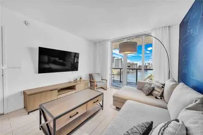 a living room with a couch and a tv at Stylish Miami Beach Getaway, Ocean Views & Gourmet Kitchen -12A in Hallandale Beach