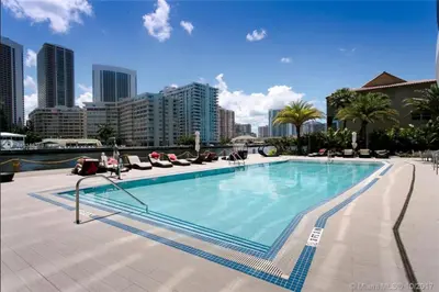 a large swimming pool with chairs and a city at Cozy BeachWalk Nest 2 Full Beds, Steps to Ocean -2010B in Hallandale Beach